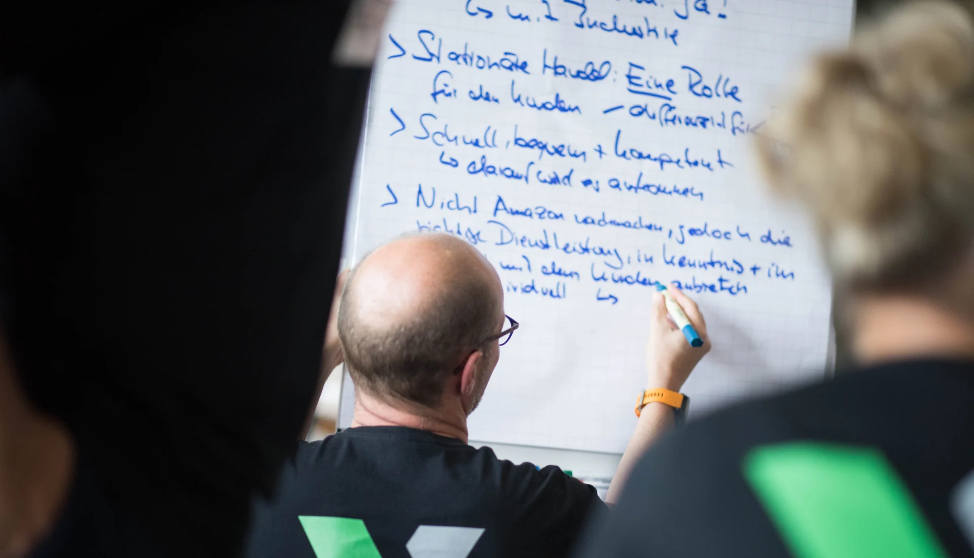 Teilnehmer notiert Handlungsfelder auf einem Flipchart im Strategieworkshop