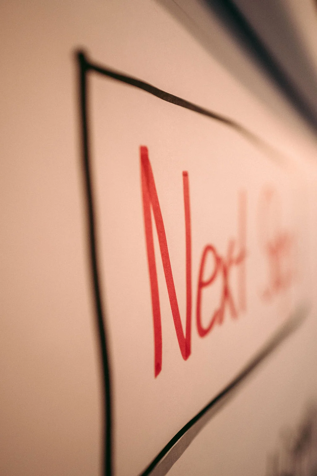 Whiteboard mit dem handgeschriebenen Wort Next Step in Rot