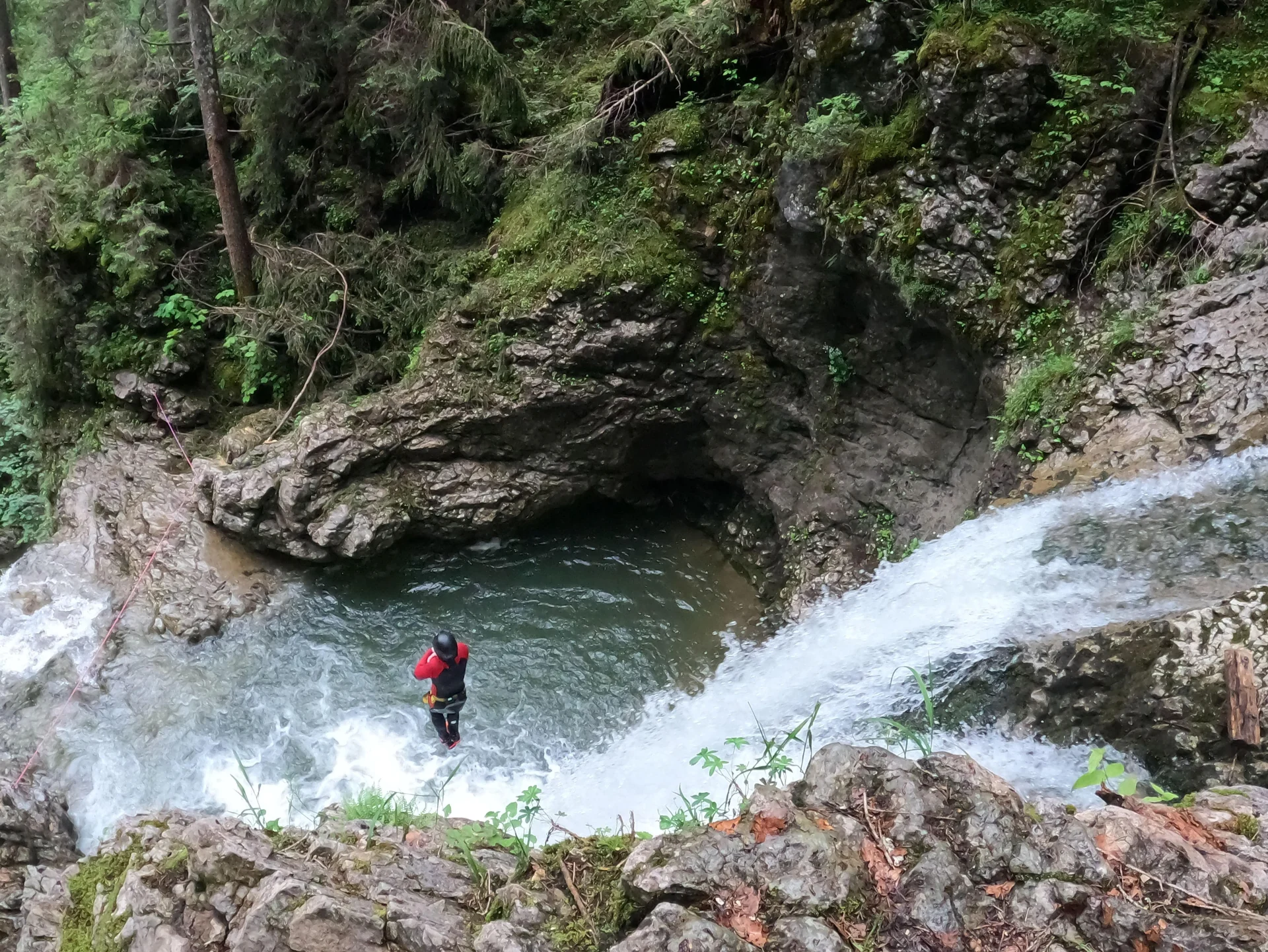 Teilnehmer beim Canyoning unterhalb eines Wasserfalls in der Schlucht