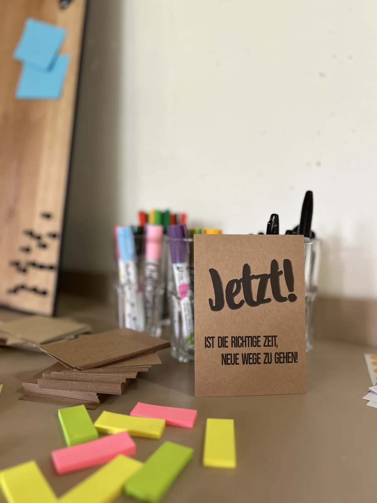 Karte mit der Aufschrift „Jetzt! Ist die richtige Zeit, neue Wege zu gehen“ zwischen Stiften