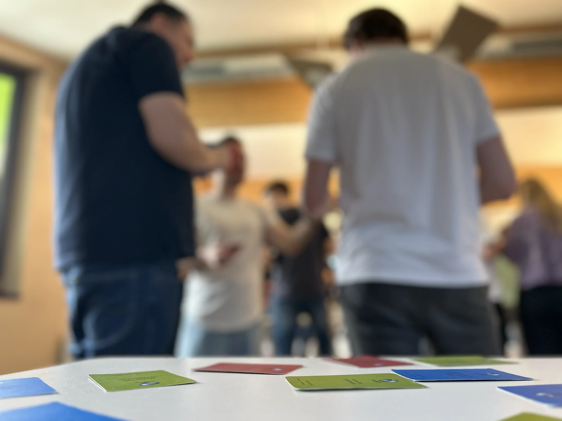 Moderationskarten auf dem Tisch, dahinter Teilnehmende im Gespräch